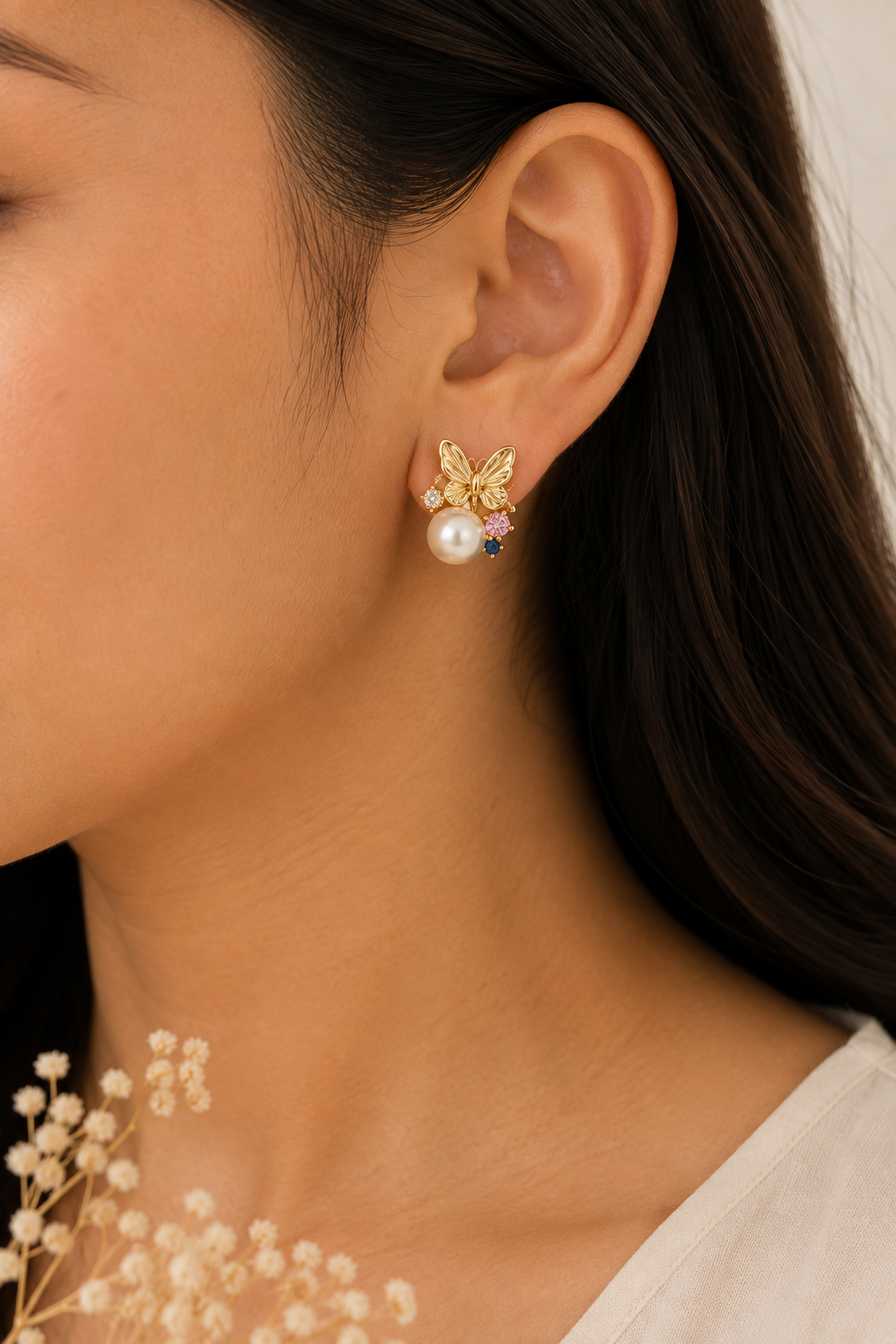 Butterfly Pearl Bloom Earrings worn on the ear, gold-tone butterfly above a round pearl