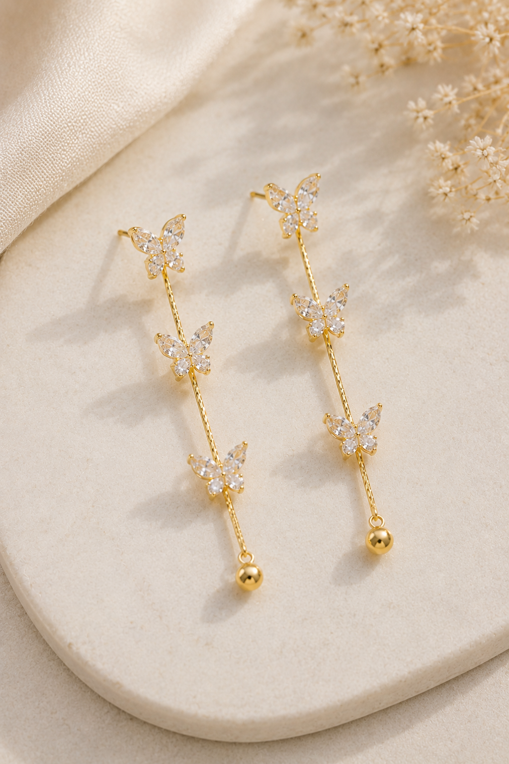 Butterfly Whisper Earrings shown flat with the full chain drop visible