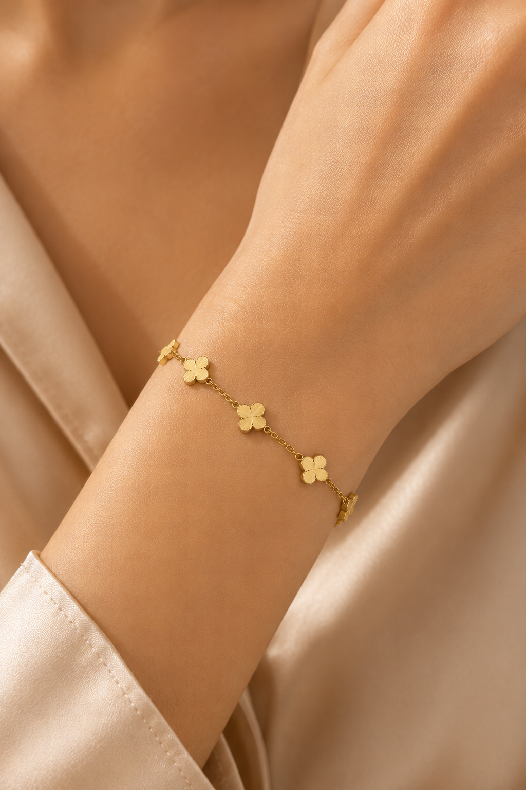 Clovera Charm Bracelet worn on the wrist, five gold-tone petal motifs on a fine chain